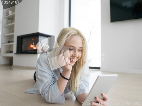 Image of woman using tablet computer in front of fireplace