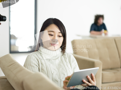 Image of asian woman using Digital Tablet on sofa