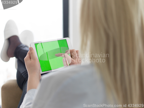 Image of young woman using tablet computer in front of fireplace