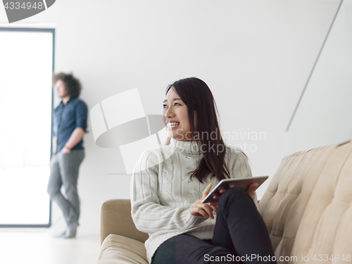 Image of multiethnic couple at home using tablet computers