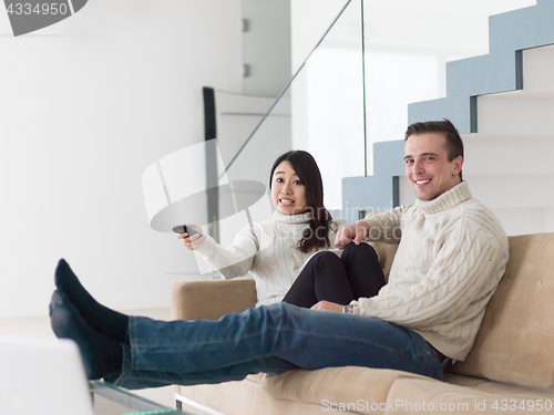 Image of multiethnic couple on the sofa watching television