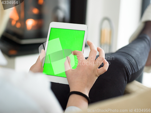 Image of young woman using tablet computer in front of fireplace