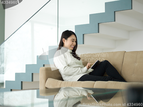 Image of asian woman using Digital Tablet on sofa