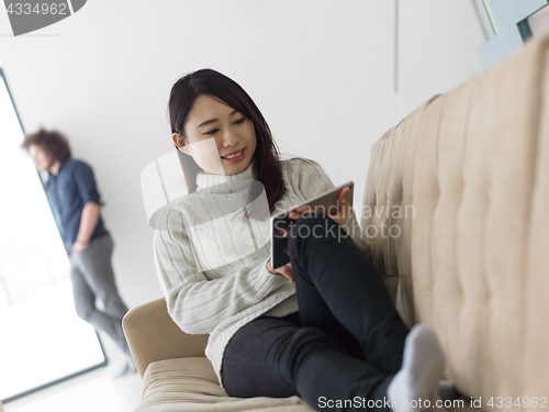 Image of multiethnic couple at home using tablet computers