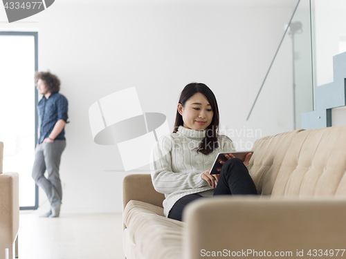 Image of multiethnic couple at home using tablet computers