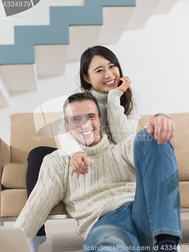 Image of happy multiethnic couple relaxing at home