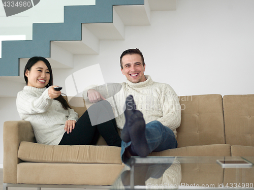 Image of multiethnic couple on the sofa watching television