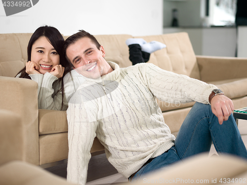 Image of happy multiethnic couple relaxing at home