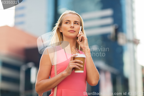 Image of woman with coffee calling on smartphone in city