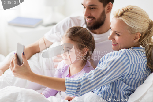 Image of happy family taking selfie by smartphone at home