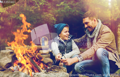 Image of father and son roasting marshmallow over campfire