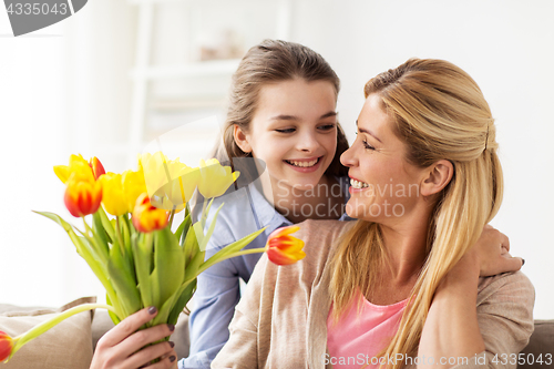 Image of happy girl giving flowers to mother at home