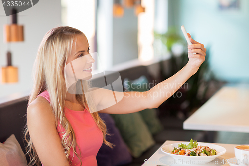 Image of woman with smartphone taking selfie at restaurant