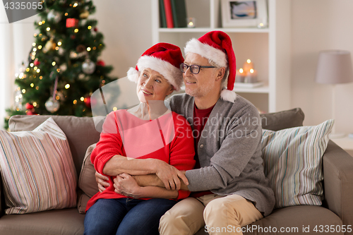 Image of happy senior couple in santa hats at christmas