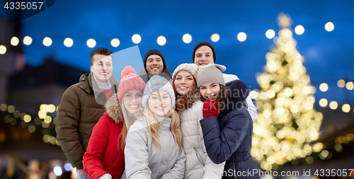 Image of happy friends taking selfie outdoors at christmas