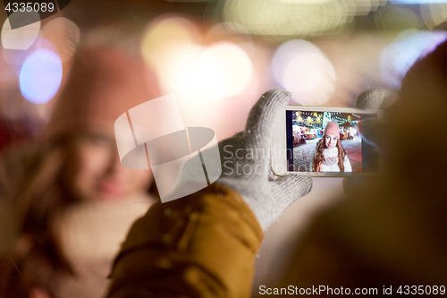 Image of hand with woman christmas picture on smartphone  