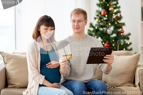 Image of man and pregnant wife shopping online at christmas