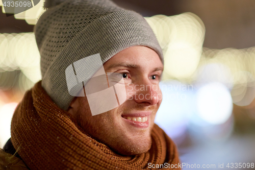 Image of happy young man over christmas lights in winter