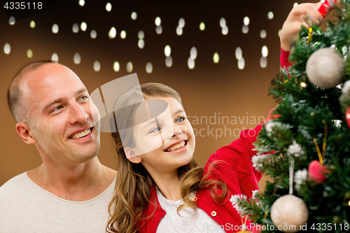 Image of happy family decorating christmas tree at home