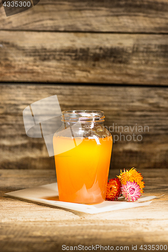 Image of The bowl with honey on wooden table.The bank of honey stay near wooden spoon