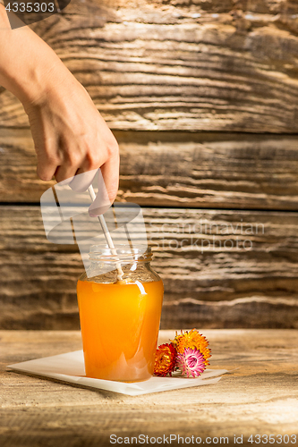 Image of The bowl with honey on wooden table.The bank of honey stay near wooden spoon