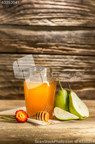 Image of The bowl with honey on wooden table.The bank of honey stay near wooden spoon