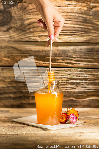 Image of The bowl with honey on wooden table.The bank of honey stay near wooden spoon