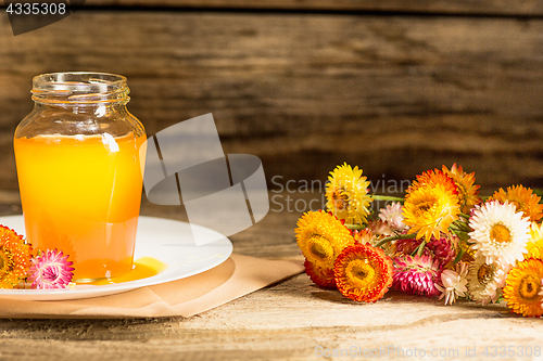 Image of The bowl with honey on wooden table.The bank of honey stay near wooden spoon