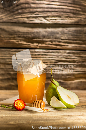 Image of The bowl with honey on wooden table.The bank of honey stay near wooden spoon