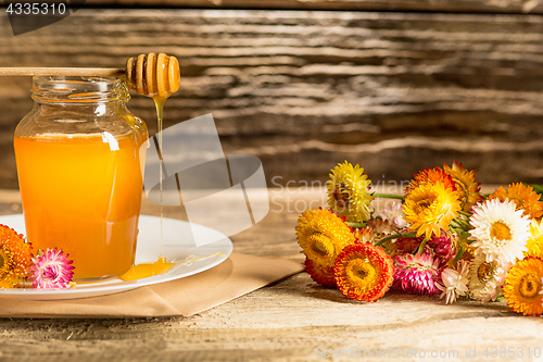 Image of The bowl with honey on wooden table.The bank of honey stay near wooden spoon