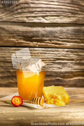 Image of The bowl with honey on wooden table.The bank of honey stay near wooden spoon