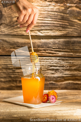 Image of The bowl with honey on wooden table.The bank of honey stay near wooden spoon