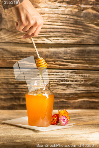 Image of The bowl with honey on wooden table.The bank of honey stay near wooden spoon