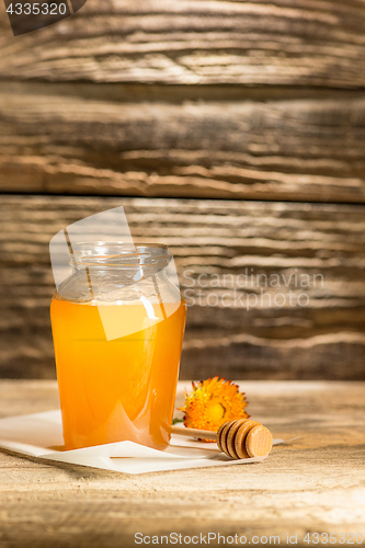 Image of The bowl with honey on wooden table.The bank of honey stay near wooden spoon