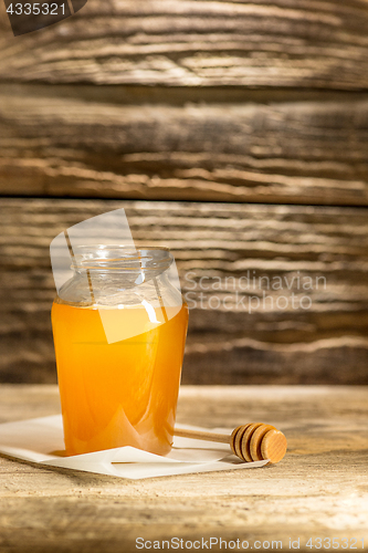 Image of The bowl with honey on wooden table.The bank of honey stay near wooden spoon