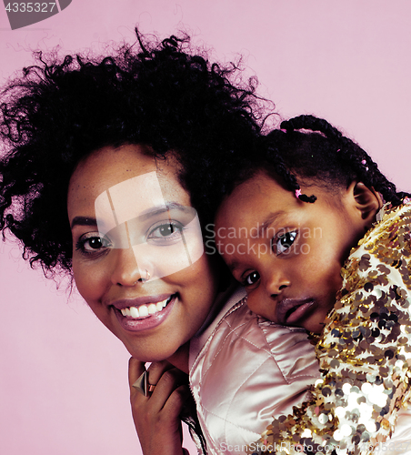 Image of young pretty african-american mother with little cute daughter hugging, happy smiling on pink background, lifestyle modern people concept