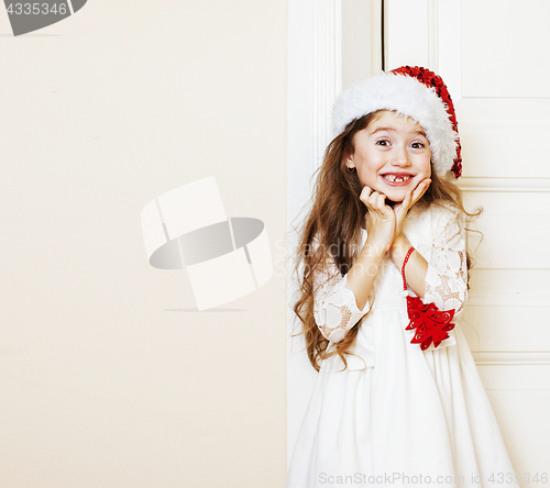 Image of little cute girl in santas red hat waiting for Christmas gifts. 