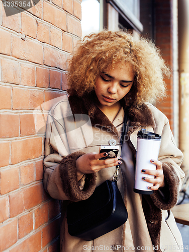 Image of young pretty african american women drinking coffee outside in c