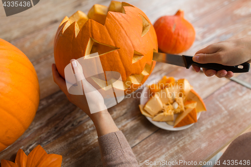 Image of close up of woman carving halloween pumpkin