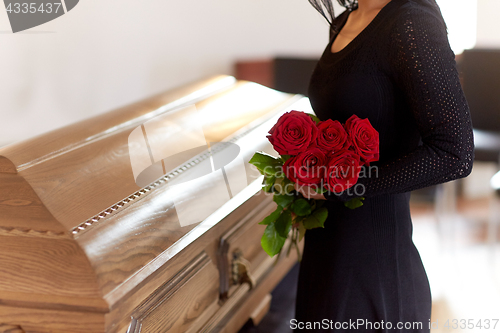 Image of woman with red roses and coffin at funeral