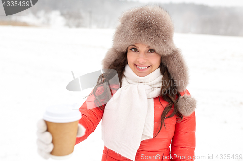 Image of happy woman in winter fur hat with coffee outdoors