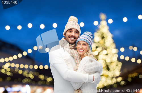 Image of happy couple hugging over christmas lights