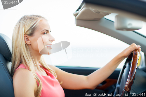 Image of happy young woman driving convertible car