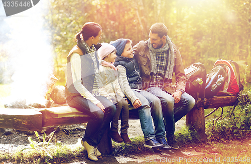 Image of happy family sitting on bench and talking at camp