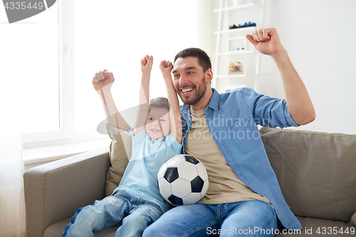 Image of father and son watching soccer on tv at home