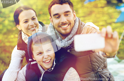 Image of family with smartphone taking selfie at campsite