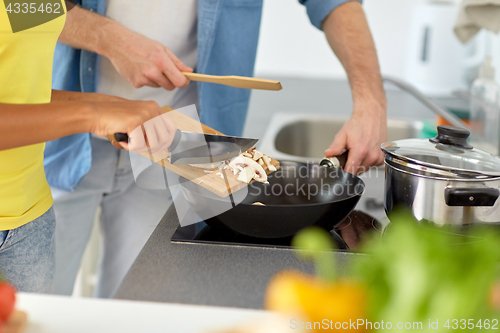 Image of multiethnic couple cooking food at home kitchen