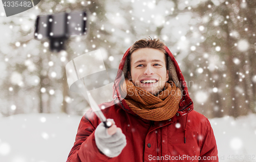 Image of happy man taking selfie by smartphone in winter