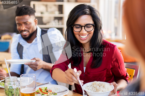 Image of happy friends eating at restaurant