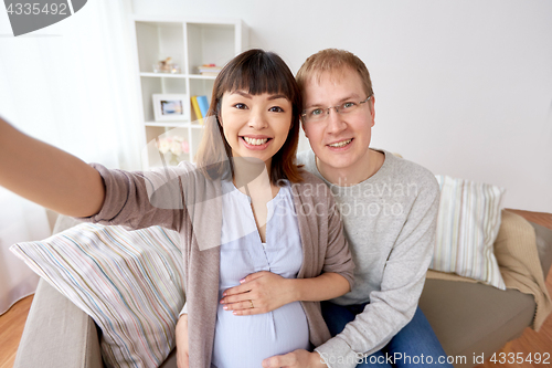 Image of pregnant woman with husband taking selfie at home